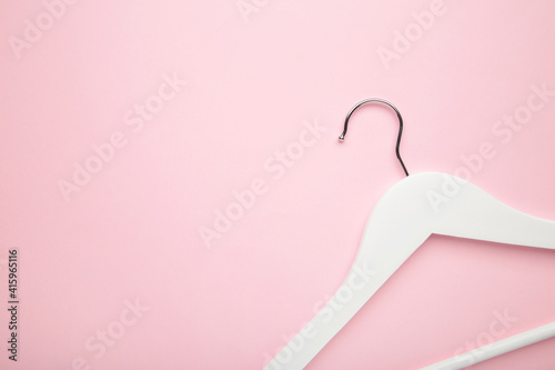 One wooden white hanger on pink background.