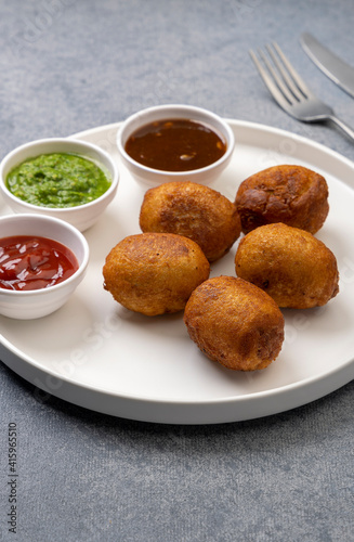 bread rolls stuffed with potatoes served with green and red sauces