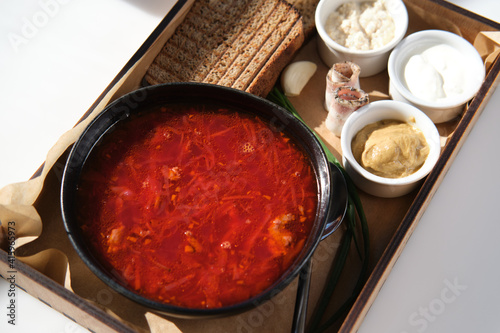 Russian or Ukrainian national soup, borscht with lard, horseradish and sour cream on a wooden tray in a cafe or restaurant. top view
