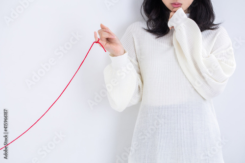 Foto 白い服を着た女性が赤い糸を指につけている　運命　恋愛　出会い love