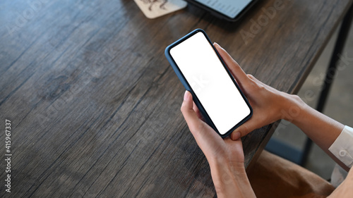 Cropped shot young female hands holding smart phone with white screen.