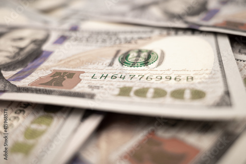 Pile of dollars lies on the table. One hundred dollar bills dumps on table. Background for design from lot of money. Blurred focus. Close-up. Side view