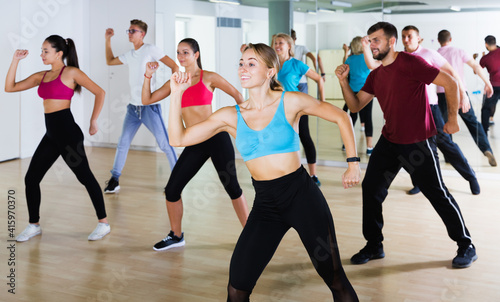 Positive different ages people learning swing steps at dance class and smiling