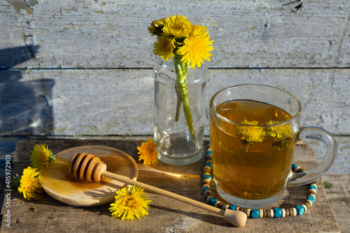 Medicinal Tea from dandelion in  glass cup with honey dandelion against a blue rustic wooden wall  with copy space photo