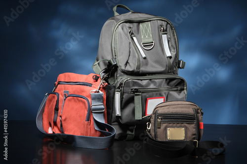 Bags of different types and sizes stand side by side. Urban backpack next to small bags. Three bags are on table. Concept - shop of handbag and backpacks. Sale of modern urban backpacks.