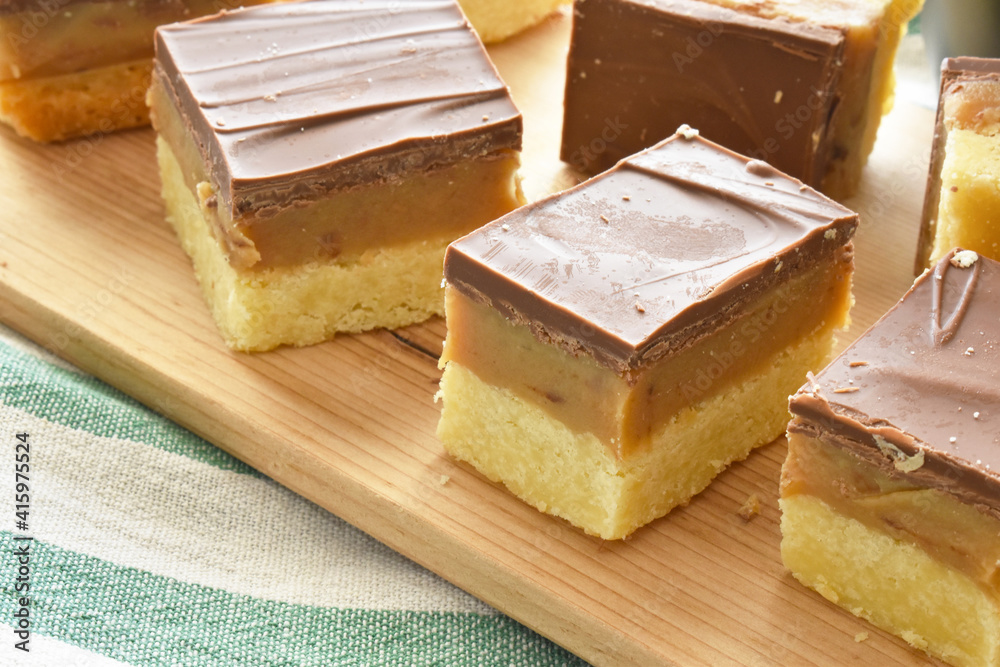 Millionaire's shortbread, caramel shortcake, or millionaire's slice on a chopping board. Millionaire's shortbread, caramel shortcake, or millionaire's slice on a chopping board.