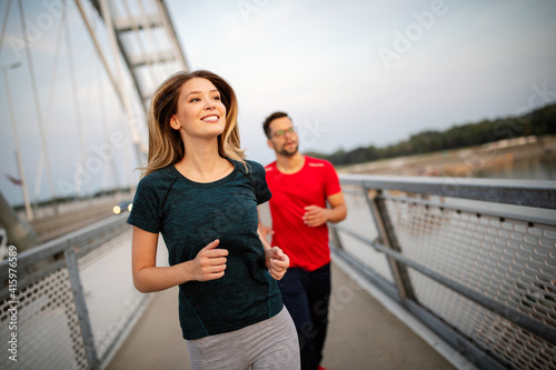Early morning workout. Happy couple running across the bridge