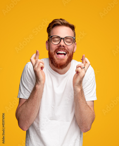 Cheerful man crossing fingers and making wish photo