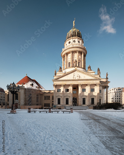 Gendarmenmarkt historic square in Berlin with French Cathedral. Picture taken n a bright Winter day with blue sky and snow.