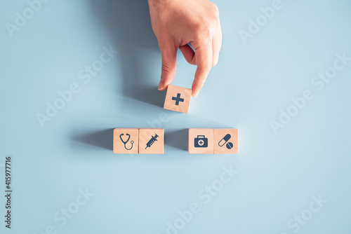 Health medical Insurance Concept, Hand arranging wood cube with medical symbol on pastel blue background, copy space.