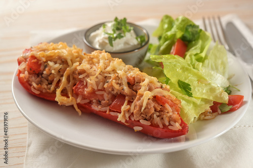 Delicious baked pointed bell pepper with rice, tomatoes, tuna and cheese on a white plate with dip and lettuce salad,