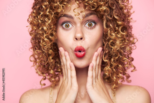 Attractive woman Surprised look and narrow lips of the hand near the face curly hair 