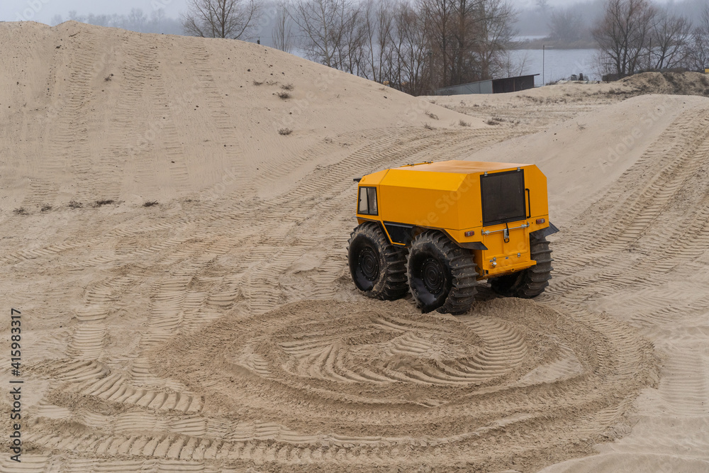 Yellow all-terrain vehicle driving and leaving twisted marks in the sand Yellow all-terrain vehicle driving and leaving twisted marks in the sand