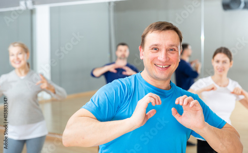 Portrait of emotional man doing exercises during group class in dance center