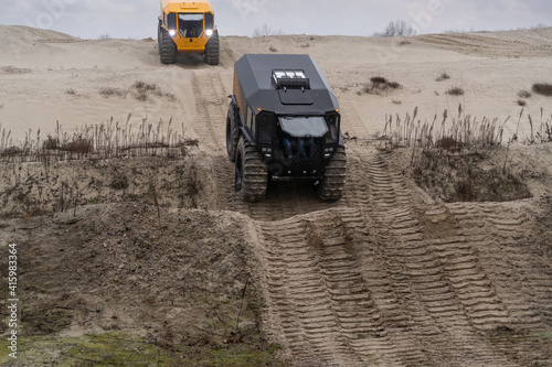 Two off-road vehicles driving in a sandy area