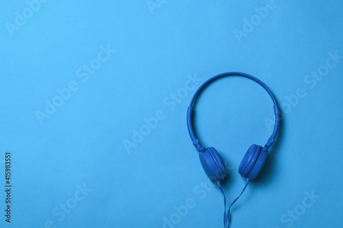 Blue headphones with a blue wire on a blue background.