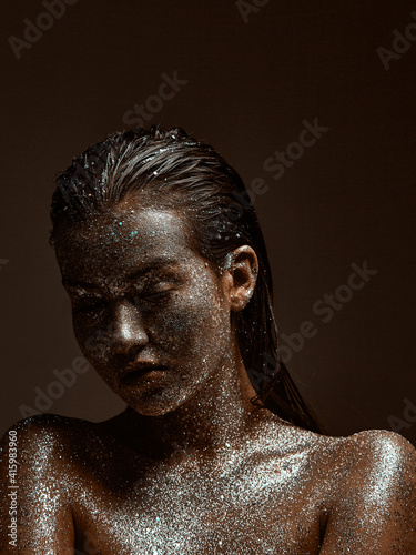 Glittering silver female body art , young beautiful naked girl with wet hair, skin in sparkles, studio beauty portrait