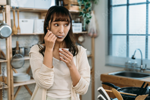 A pretty Asian girl show us that she ate the tasty new fruit yogurt in the kitchen. healthy breakfast in the cozy morning.