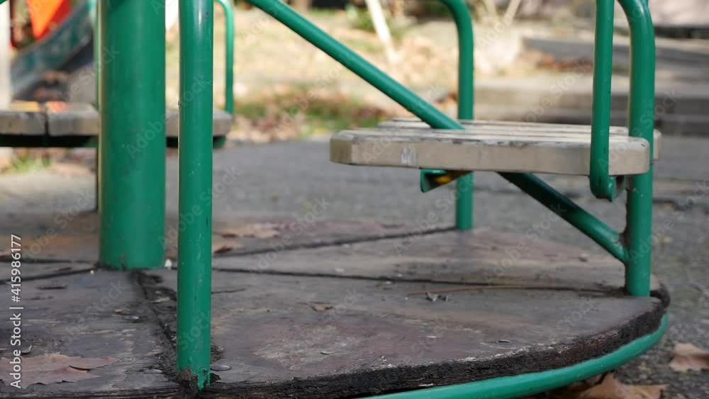 Old metal carousel for children is moving. Empty abandoned city with a playground. Empty swing. Concept of child abduction. Kidnapping Old metal carousel for children is moving. Empty abandoned city with a playground. Empty swing. Concept of child abduction. Kidnapping