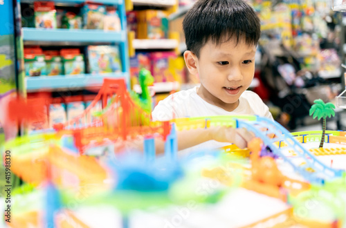 Happy kindergarten kid boy playing with rail road toy game,asian little child having fun enjoy with toys car on display in department store,educational toys for children,education development concept