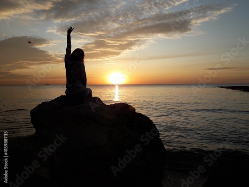 Girl sits on a stone and looks at the dawn at sunrise
