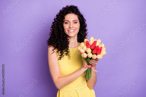 Portrait of gorgeous cheerful person hands hold flowers toothy smile look camera isolated on purple color background