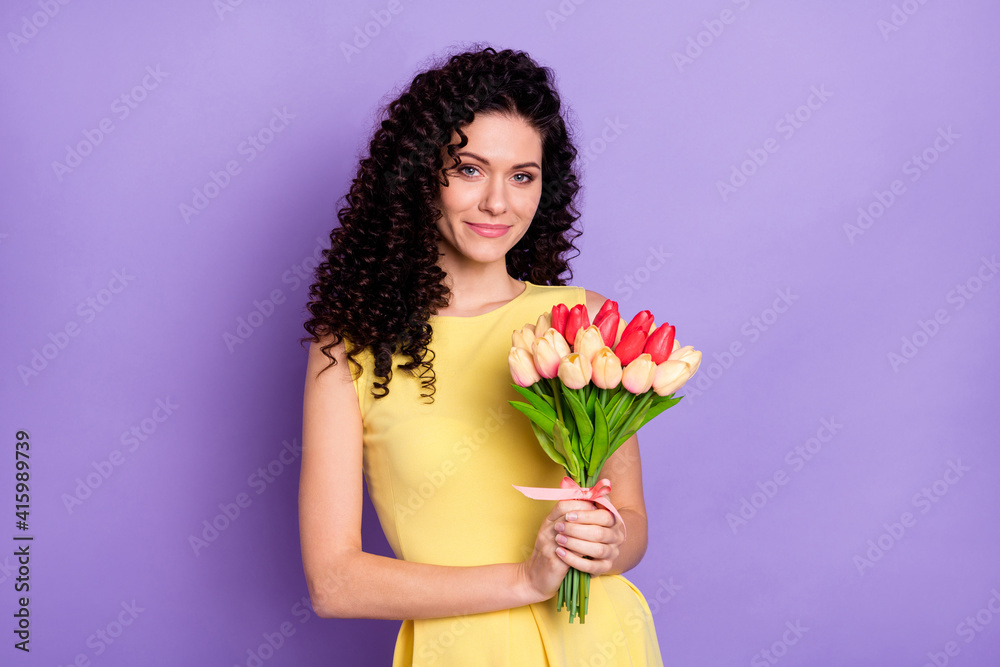 Photo of charming young lady hold bunch tulips look camera wear yellow dress isolated violet background
