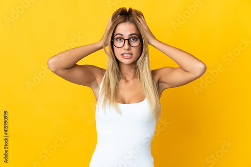 Young blonde woman isolated on yellow background doing nervous gesture
