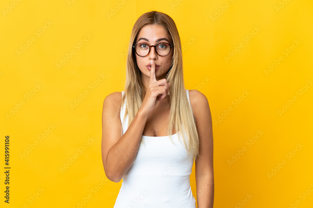 Young blonde woman isolated on yellow background showing a sign of silence gesture putting finger in mouth Young blonde woman isolated on yellow background showing a sign of silence gesture putting finger in mouth