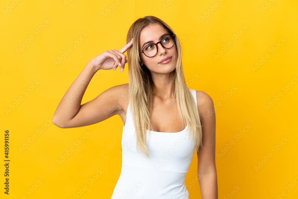 Young blonde woman isolated on yellow background making the gesture of madness putting finger on the head Young blonde woman isolated on yellow background making the gesture of madness putting finger on the head
