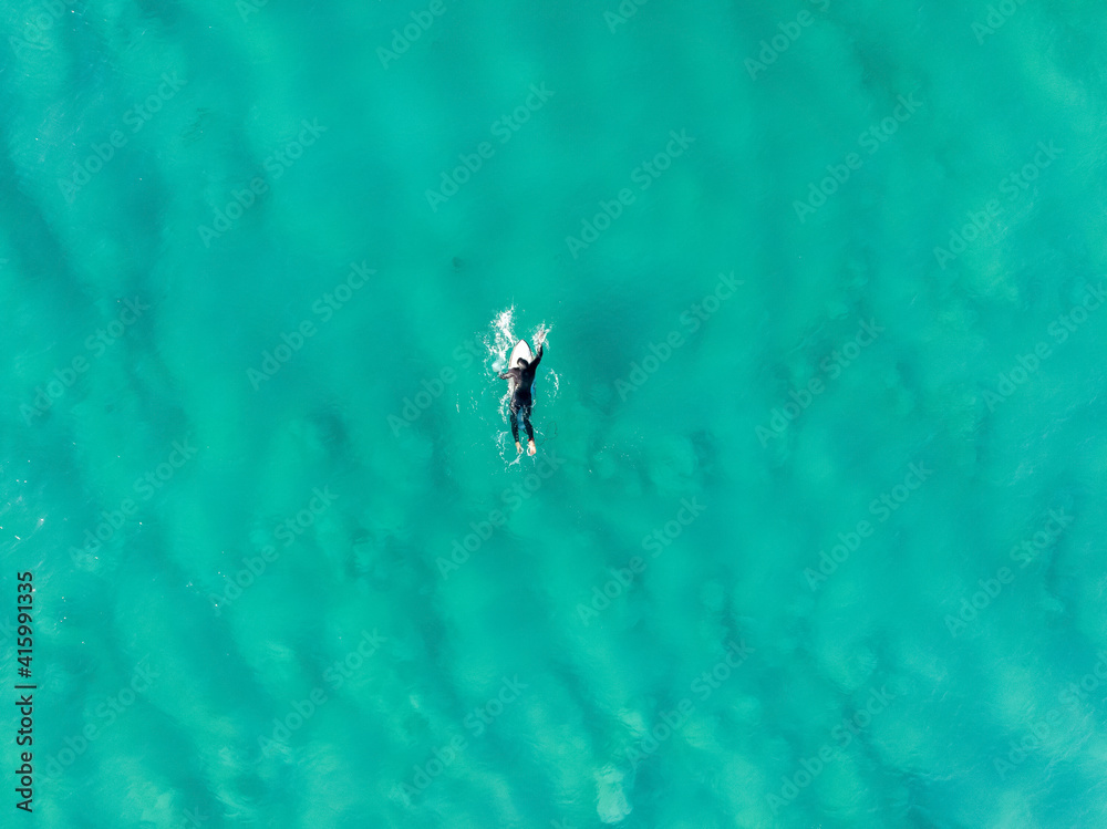 Aerial view of surfer swimming in clear Atlantic Ocean at Llandudno beach, Cape Town, South Africa. Aerial view of surfer swimming in clear Atlantic Ocean at Llandudno beach, Cape Town, South Africa.
