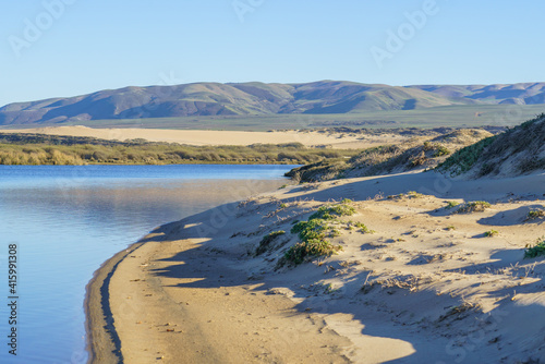 Sand dunes, blue river, green hills and mountains on background. Guadalupe-Nipomo Dunes, CA