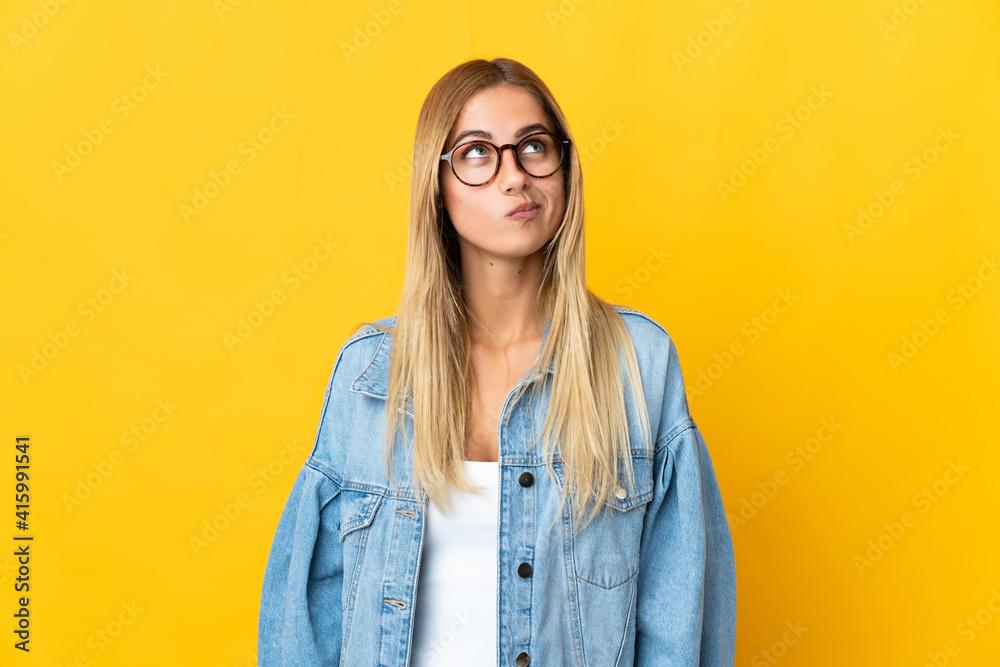 Young blonde woman isolated on yellow background and looking up
