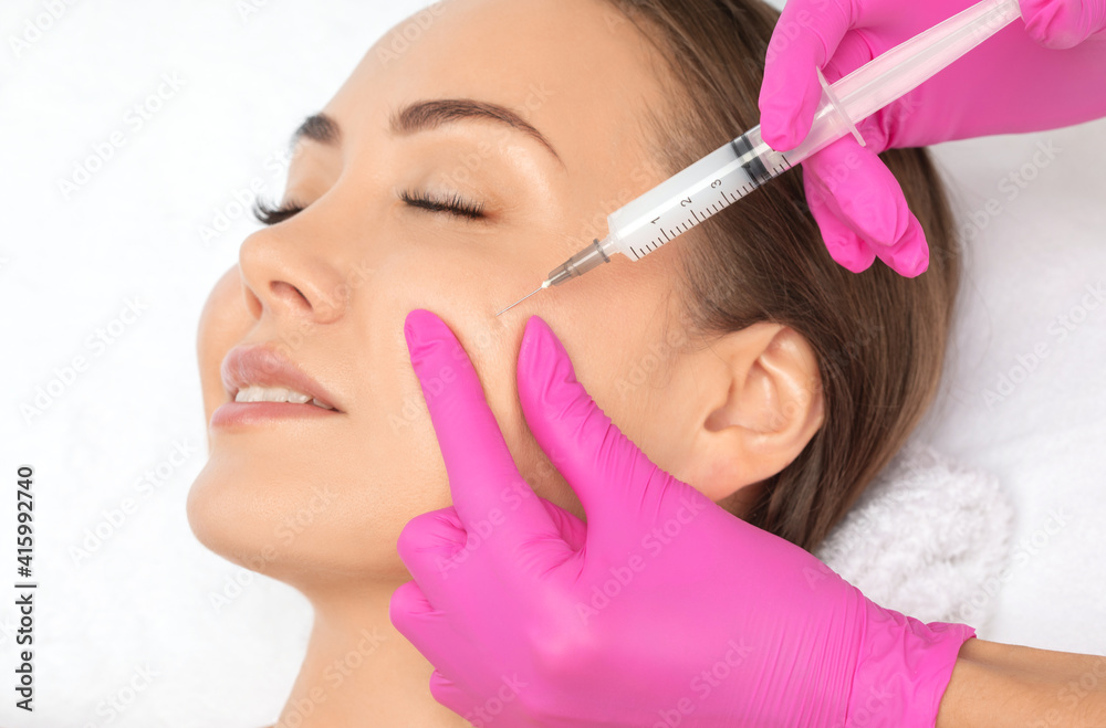 Cosmetologist makes lipolytic injections to burn fat on the chin, cheeks and neck of a woman against double chin. Female aesthetic cosmetology in a beauty salon.Cosmetology concept. Cosmetologist makes lipolytic injections to burn fat on the chin, cheeks and neck of a woman against double chin. Female aesthetic cosmetology in a beauty salon.Cosmetology concept.