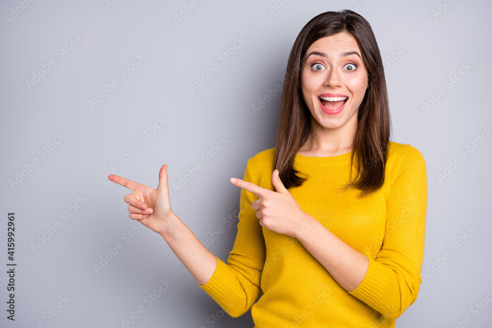Photo of young happy excited cheerful positive good mood girl pointing finger copyspace isolated on grey color background Photo of young happy excited cheerful positive good mood girl pointing finger copyspace isolated on grey color background