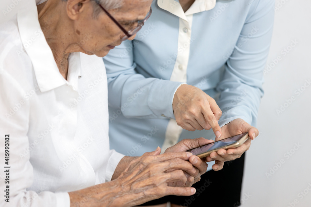 Asian woman teaching the old people how to use mobile phone,senior grandmother learning to use smartphone with a help of adult daughter,learn electronic gadget,study modern technology for elderly Asian woman teaching the old people how to use mobile phone,senior grandmother learning to use smartphone with a help of adult daughter,learn electronic gadget,study modern technology for elderly