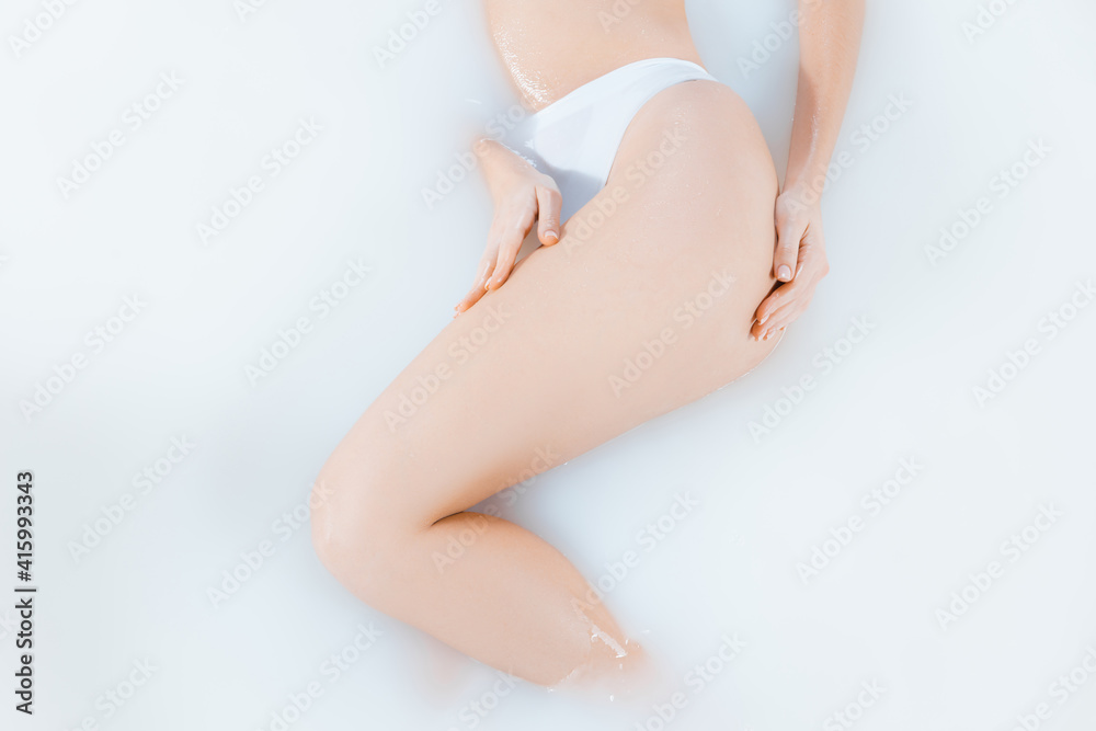 Legs and belly. Close up female body in the milk bath with soft white glowing. Copyspace for advertising. Beauty, fashion, style, bodycare concept. Attractive caucasian model in milky colored foam.