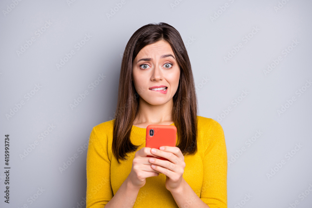 Photo of young unhappy upset guilty girl using smartphone receive bad comment isolated on grey color background Photo of young unhappy upset guilty girl using smartphone receive bad comment isolated on grey color background