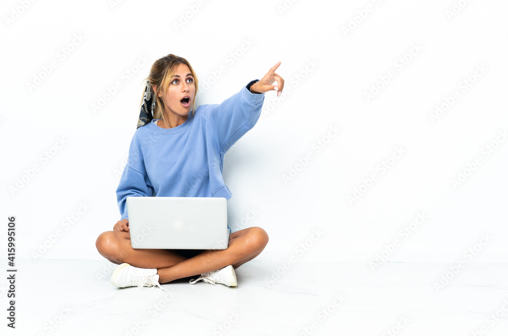 Young blonde Uruguayan girl with the laptop isolated on white background pointing away Young blonde Uruguayan girl with the laptop isolated on white background pointing away