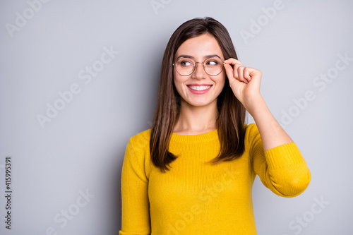 Portrait of attractive cheerful clever girl touching specs looking aside copy space isolated over grey color background
