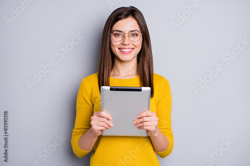 Portrait of pretty cheerful girl holding in hands using tablet pda isolated over grey color background