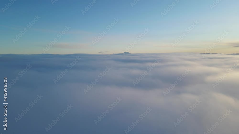 Flying over clouds at sunset time. The highest mountain in Southern Norway is sticking up out of clouds in a far. Drone footage Flying over clouds at sunset time. The highest mountain in Southern Norway is sticking up out of clouds in a far. Drone footage