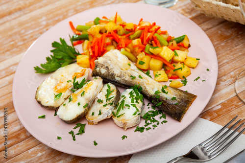 Oven baked hake with vegetable garnish and parsley
