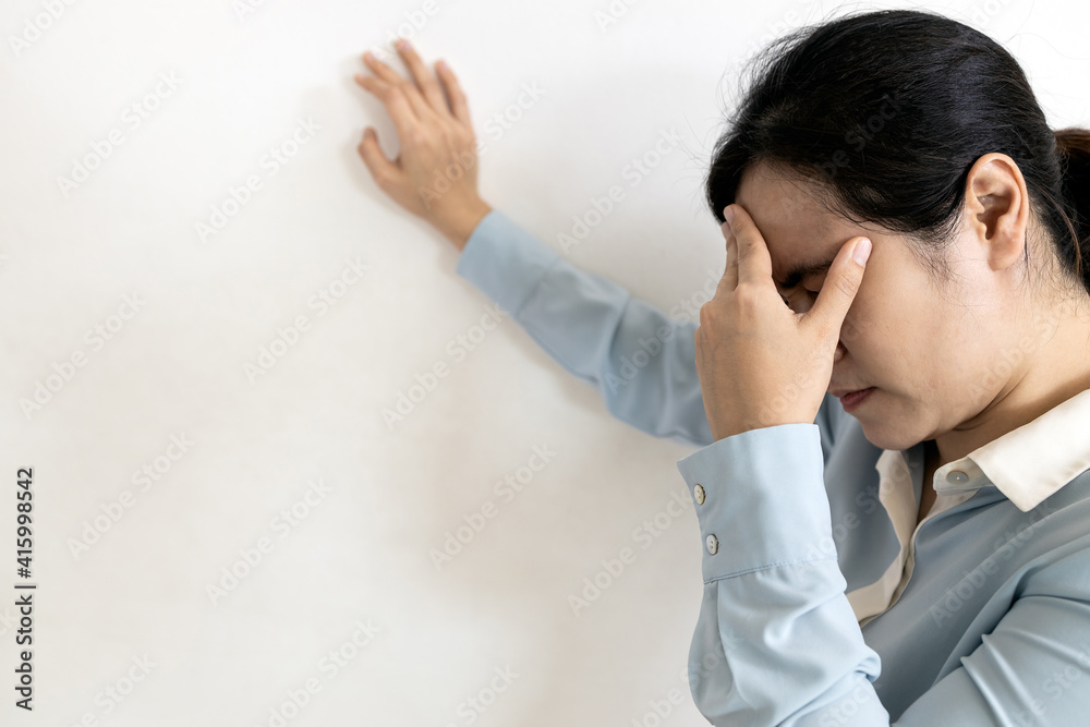 Asian woman suffering from dizziness,sensation of spinning around,losing her balance,Tired business woman touching her temple with eyes closed,stagger,symptoms of vertigo,stupor,near unconsciousness.