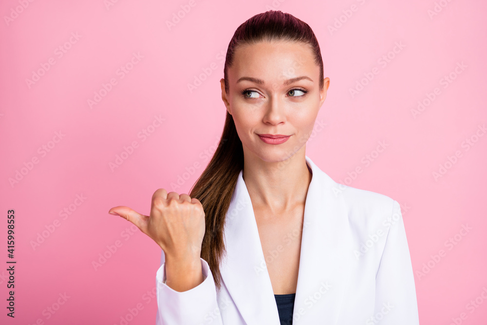 Photo of serious young woman look point thumb empty space information ad isolated on pink color background Photo of serious young woman look point thumb empty space information ad isolated on pink color background