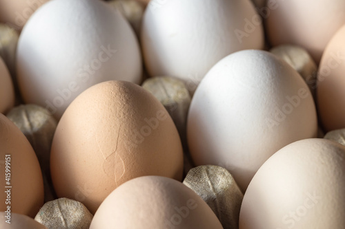 Chicken eggs in a cardboard container close-up. A damaged egg in a container.