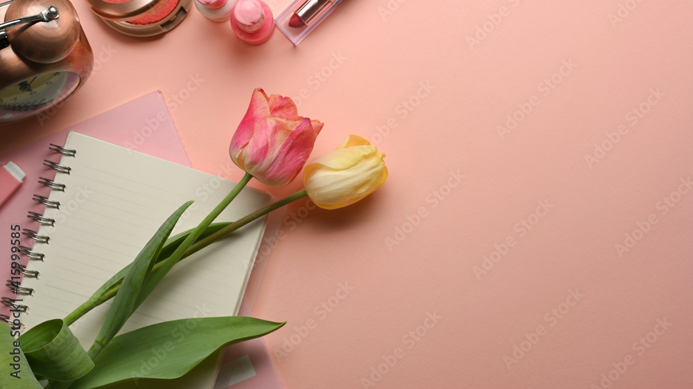 Pink feminine creative flat lay workspace with flowers, notebook and cosmetics