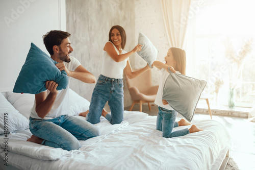 Merry little family doing pillow fight while staying at home photo