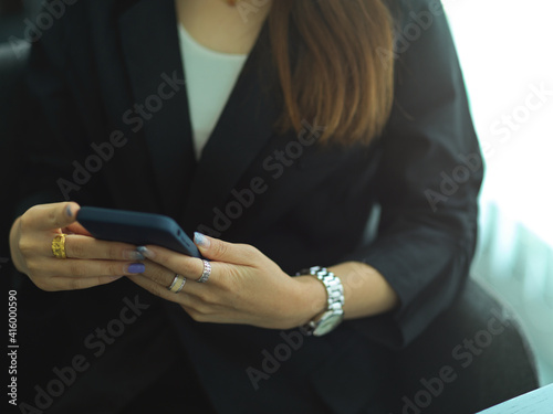 Businesswoman hand using smartphone while sitting in office room