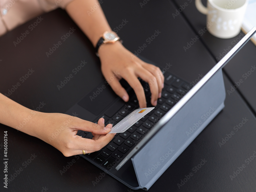 Female online paying, hand typing on tablet keyboard and holding credit card Female online paying, hand typing on tablet keyboard and holding credit card